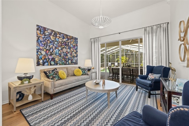 living area with wood finished floors, an inviting chandelier, a sunroom, and crown molding