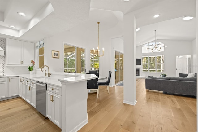 kitchen featuring dishwasher, a peninsula, an inviting chandelier, and white cabinets