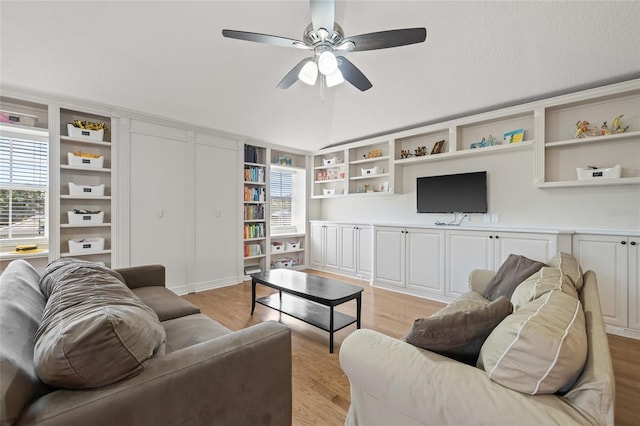 living room with light wood finished floors, vaulted ceiling, a ceiling fan, and built in shelves