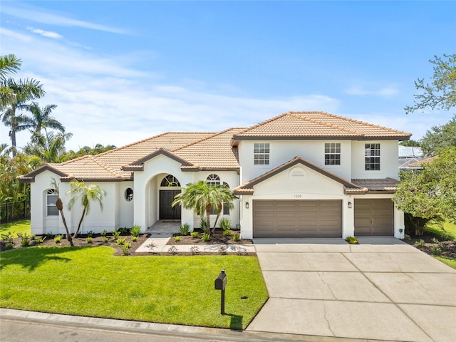 mediterranean / spanish-style house with a tile roof, driveway, a garage, a front yard, and stucco siding