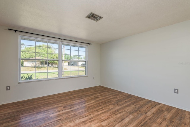 10137 Oleander Dr, Port Richey, FL 34668 - empty room featuring plenty of natural light, wood finished floors, a textured ceiling, and baseboards