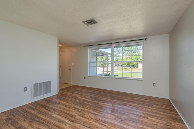 10137 Oleander Dr, Port Richey, FL 34668 - empty room featuring wood finished floors, a textured ceiling, and baseboards