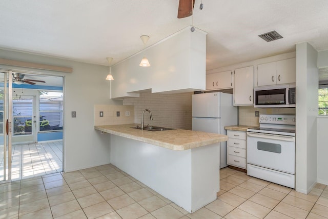 10137 Oleander Dr, Port Richey, FL 34668 - kitchen featuring white appliances, a sink, healthy amount of natural light, and a peninsula