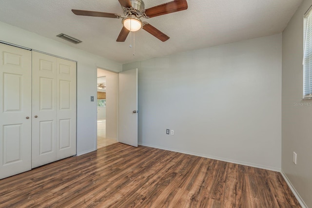 10137 Oleander Dr, Port Richey, FL 34668 - unfurnished bedroom with wood finished floors, a closet, baseboards, ceiling fan, and a textured ceiling