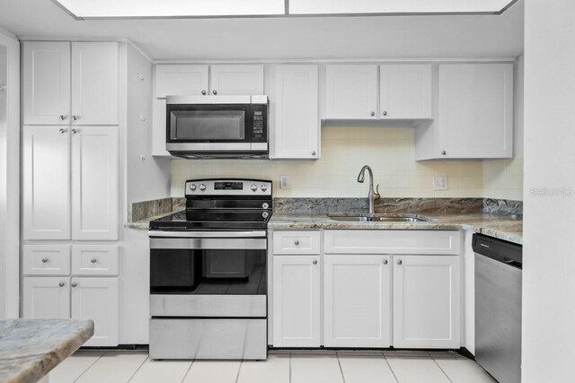 500 Glennes Ln Unit 205, Dunedin, FL 34698 - kitchen with a sink, white cabinetry, appliances with stainless steel finishes, light stone counters, and light tile patterned floors