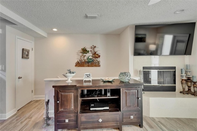 17960 Gulf Blvd Unit 111, Redington Shores, FL 33708 - bar featuring a tiled fireplace, a textured ceiling, wood finished floors, and visible vents