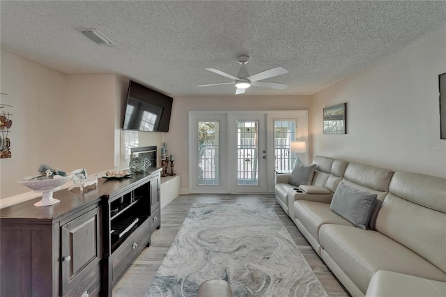 17960 Gulf Blvd Unit 111, Redington Shores, FL 33708 - living room featuring ceiling fan, light wood finished floors, a textured ceiling, baseboards, and visible vents