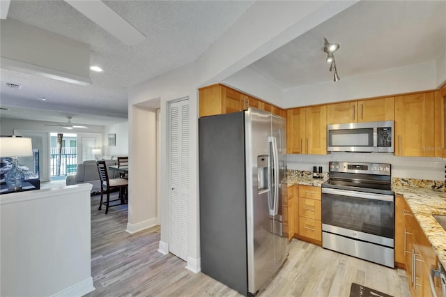 17960 Gulf Blvd Unit 111, Redington Shores, FL 33708 - kitchen with light stone countertops, baseboards, open floor plan, light wood-type flooring, and stainless steel appliances