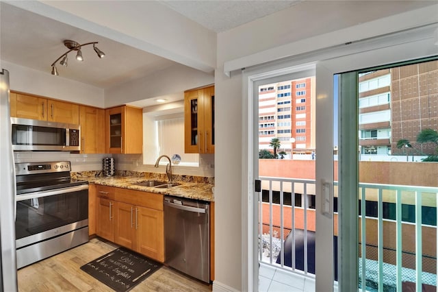 17960 Gulf Blvd Unit 111, Redington Shores, FL 33708 - kitchen with glass insert cabinets, tasteful backsplash, light stone counters, a sink, and stainless steel appliances