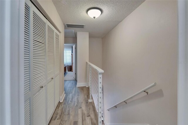17960 Gulf Blvd Unit 111, Redington Shores, FL 33708 - corridor with a textured ceiling, visible vents, baseboards, an upstairs landing, and light wood-style flooring