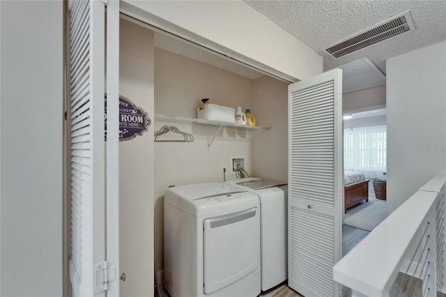 17960 Gulf Blvd Unit 111, Redington Shores, FL 33708 - laundry room featuring visible vents, laundry area, a textured ceiling, and separate washer and dryer