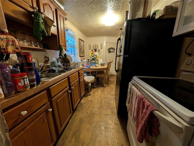 730 Citrus St, Orlando, FL 32805 - kitchen with white appliances, light wood finished floors, a sink, and brown cabinetry