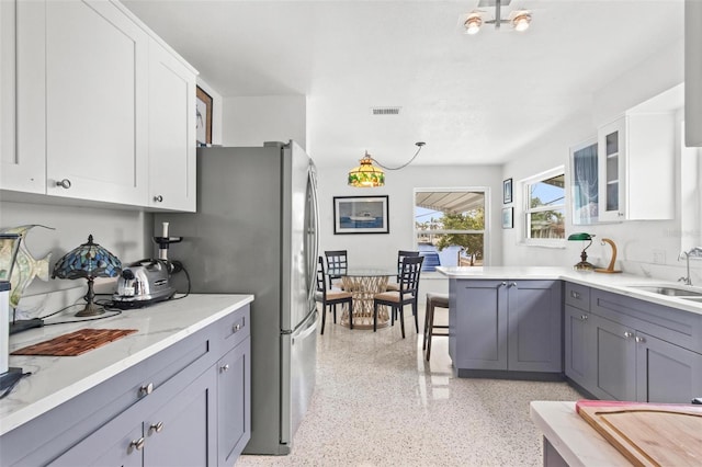 kitchen featuring a sink, light speckled floor, white cabinetry, and gray cabinets