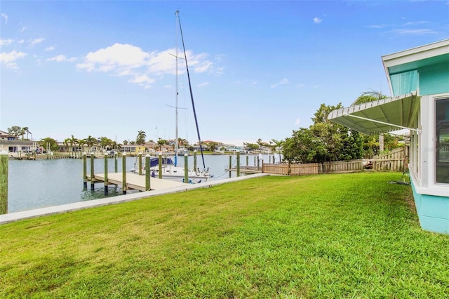 dock area with a lawn, fence, and a water view