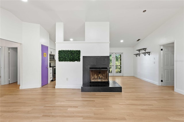 unfurnished living room with baseboards, visible vents, a fireplace with raised hearth, and light wood-style flooring