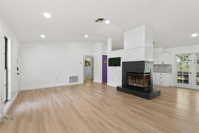unfurnished living room with vaulted ceiling, visible vents, and light wood-style flooring