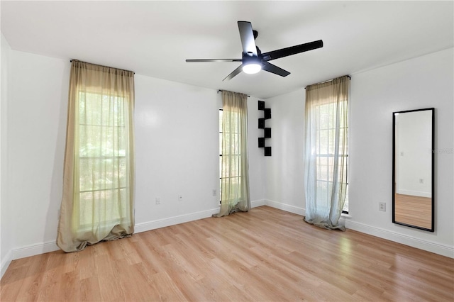 unfurnished room with light wood-type flooring, a ceiling fan, and baseboards