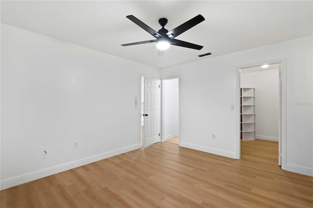unfurnished bedroom featuring a spacious closet, visible vents, light wood-type flooring, a closet, and baseboards