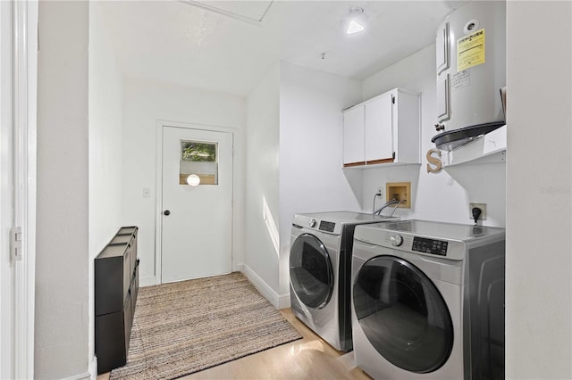 laundry area featuring baseboards, light wood-style floors, separate washer and dryer, water heater, and cabinet space