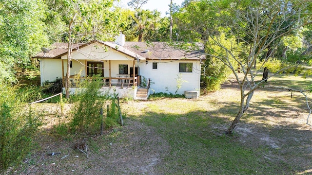back of property featuring covered porch, cooling unit, and stucco siding