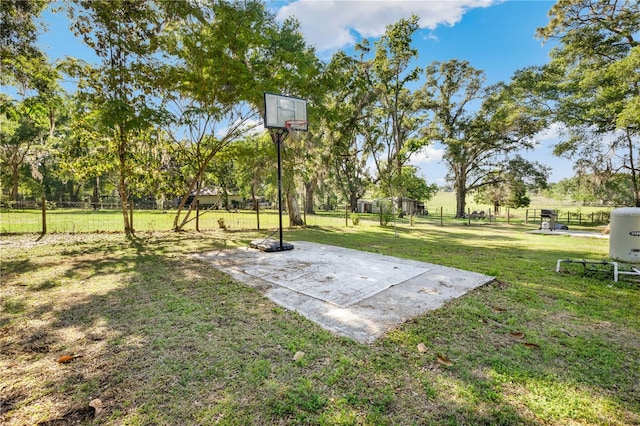 view of yard featuring fence and basketball hoop
