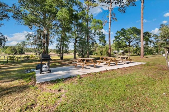 view of community with a yard, a patio area, and fence