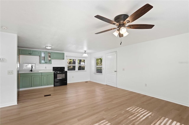 unfurnished living room featuring ceiling fan, baseboards, a sink, and light wood-style flooring