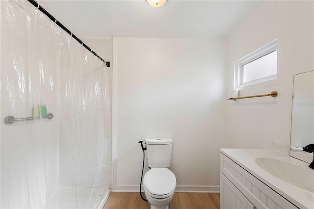 bathroom featuring a stall shower, wood finished floors, vanity, and toilet