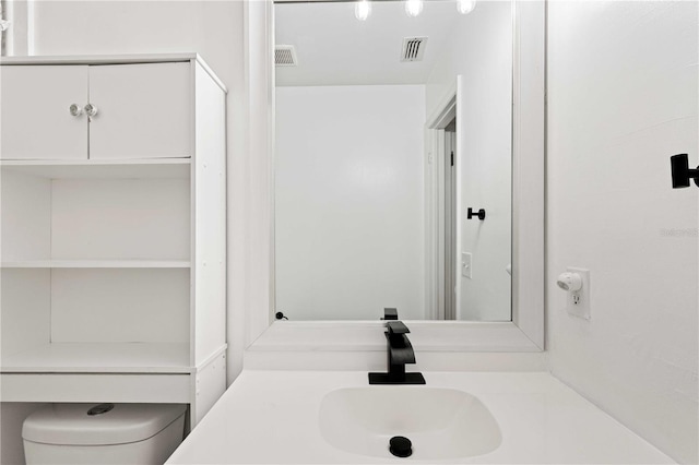 bathroom with toilet, vanity, and visible vents