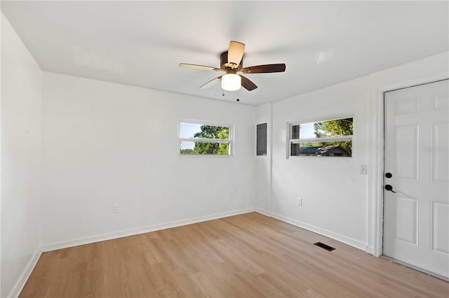 empty room with baseboards, a ceiling fan, light wood-style floors, and visible vents