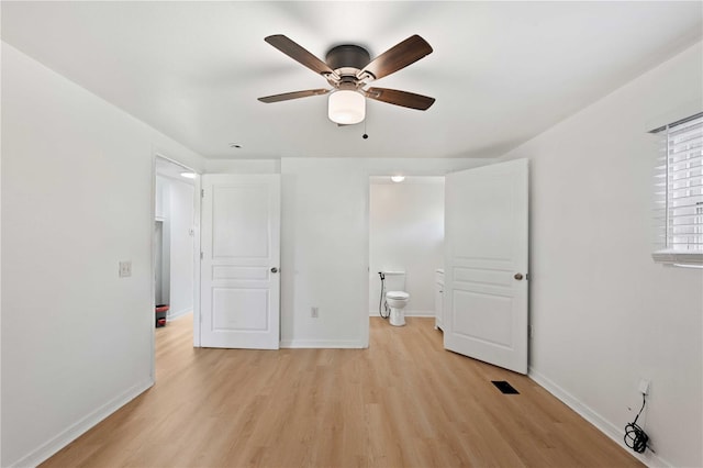 unfurnished bedroom with light wood-type flooring, baseboards, visible vents, a ceiling fan, and connected bathroom