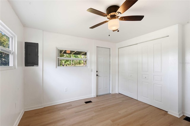unfurnished bedroom with light wood-style flooring, electric panel, multiple windows, and visible vents