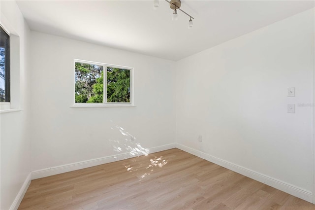 unfurnished room with light wood-type flooring and baseboards