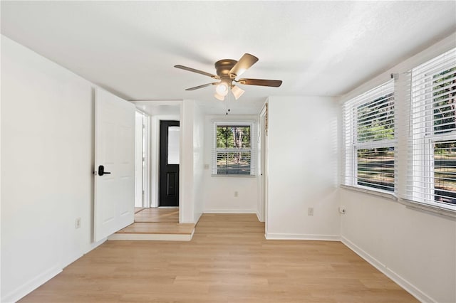 empty room featuring light wood finished floors, baseboards, and ceiling fan