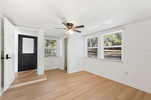 foyer entrance with ceiling fan, baseboards, and light wood-style floors