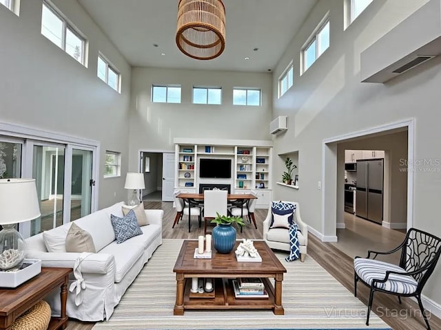 233 45th Ave, St Pete Beach, FL 33706 - living room with a towering ceiling, wood finished floors, baseboards, and a wall mounted air conditioner