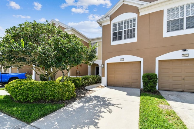 townhome / multi-family property with an attached garage, driveway, and stucco siding