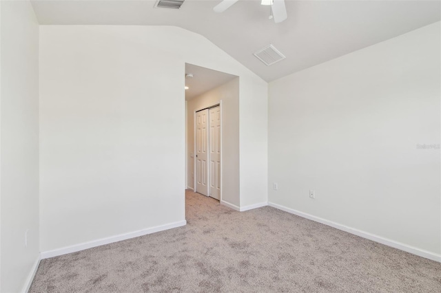 carpeted spare room featuring ceiling fan, lofted ceiling, visible vents, and baseboards