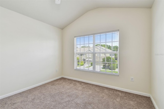 carpeted spare room featuring lofted ceiling and baseboards