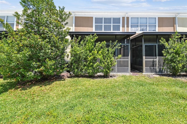 back of property featuring a sunroom, a yard, and stucco siding
