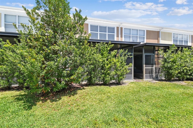 back of house featuring a lawn and a sunroom