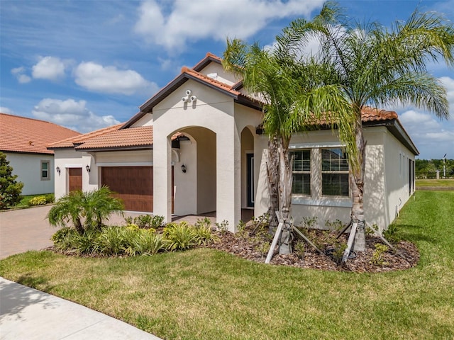 mediterranean / spanish house featuring a tile roof, driveway, an attached garage, a front yard, and stucco siding