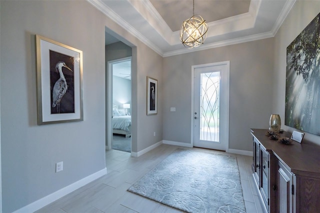 entrance foyer featuring a tray ceiling, baseboards, ornamental molding, and an inviting chandelier