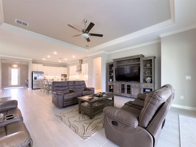 living area featuring ornamental molding, a ceiling fan, a tray ceiling, and visible vents