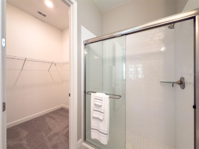 full bathroom featuring a walk in closet, baseboards, visible vents, and a stall shower