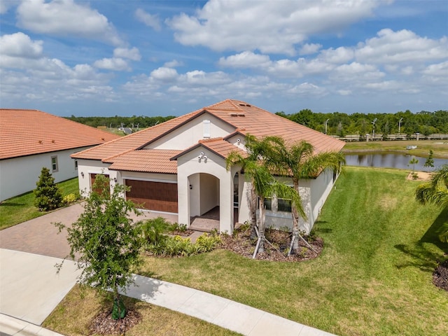 mediterranean / spanish-style home featuring concrete driveway, a water view, a tile roof, stucco siding, and a garage