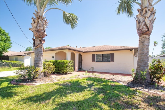 view of front of home featuring fence, concrete driveway, a front yard, and stucco siding
