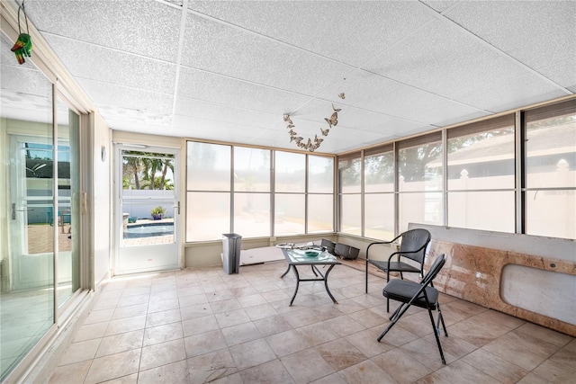 sunroom / solarium featuring tile patterned floors and a drop ceiling