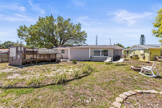 1344 Dartmouth Dr, Holiday, FL 34691 - rear view of property featuring fence, a wooden deck, an outdoor fire pit, and stucco siding