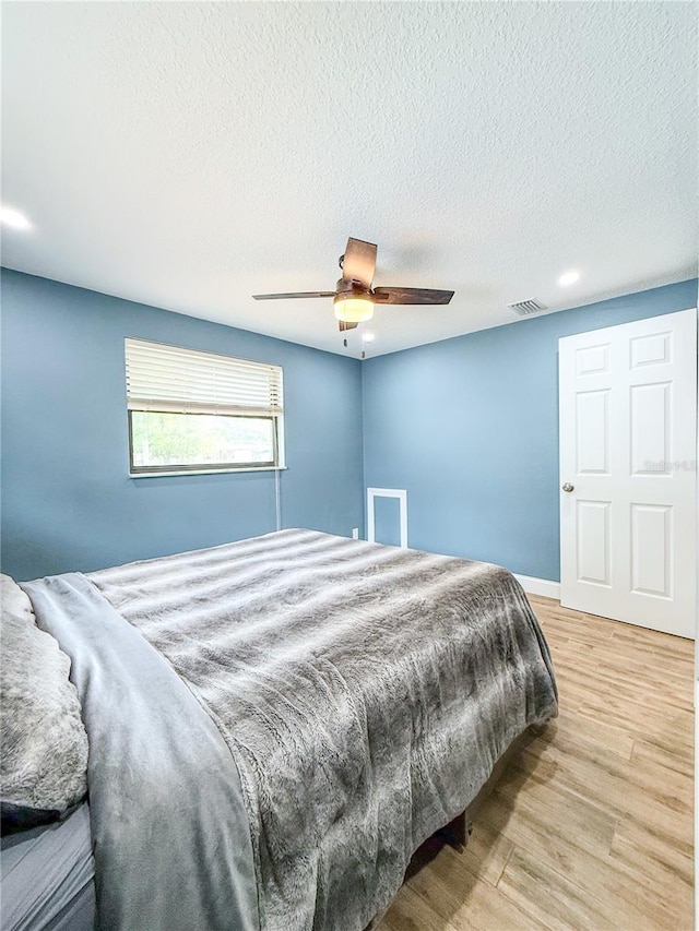 8648 78th Pl, Seminole, FL 33777 - bedroom featuring wood finished floors, ceiling fan, and a textured ceiling